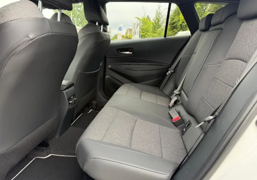 Vue côté droit de l'habitacle arrière de la Toyota Corolla Touring Sport 2025, sièges bi-matière gris et noir.