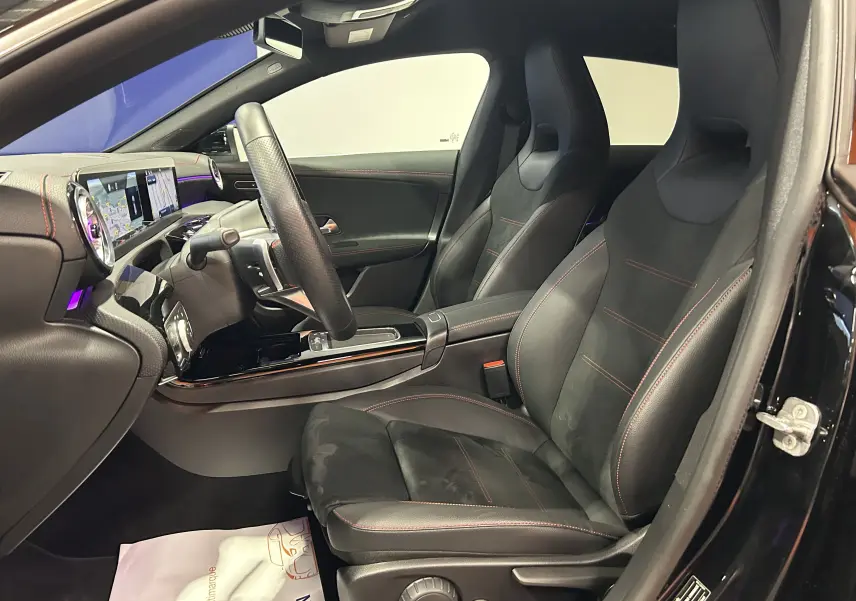 Intérieur noir avec sièges sport en cuir et alcantara, tableau de bord digital et éclairage d'ambiance violet côté conducteur.