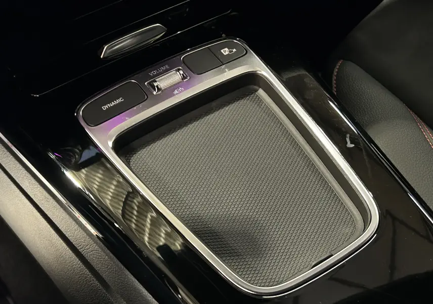 Gros plan sur la console centrale noire brillante de la Mercedes Classe CLA Shooting Brake II 200D AMG avec commandes Dynamic et volume.