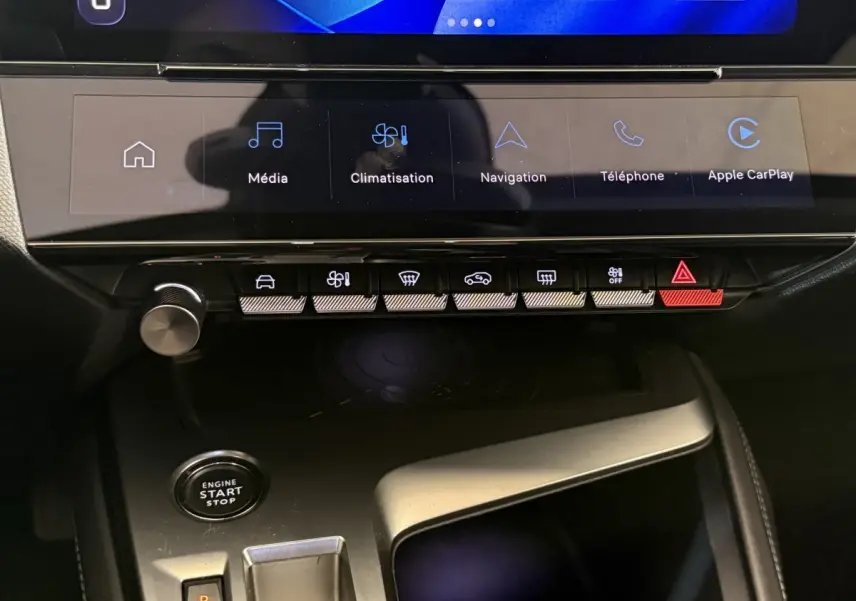 Vue rapprochée de la console centrale de la Peugeot 308 gris foncé, avec écran tactile et boutons de commande éclairés.