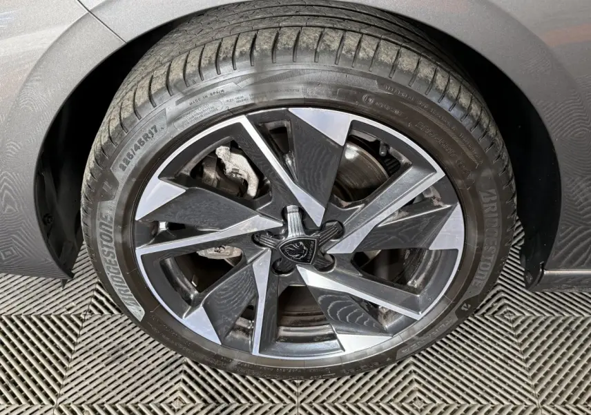 Gros plan sur la roue avant droite gris foncé d’une Peugeot 308 SW avec jante alliage au design géométrique.