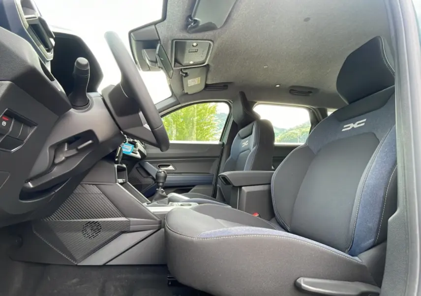 Vue intérieure côté conducteur du Dacia Bigster 2025, sièges tissu noir et bleu avec logo DC brodé.