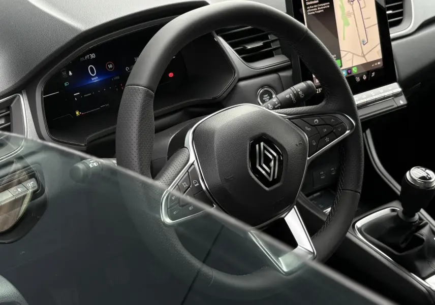 Vue rapprochée du volant noir et du levier de vitesses manuel du Renault Captur 2025 avec écran tactile vertical visible.