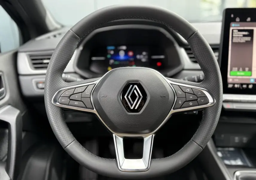 Volant en cuir perforé avec logo Renault, vue frontale centrée sur le tableau de bord numérique et écran tactile latéral.