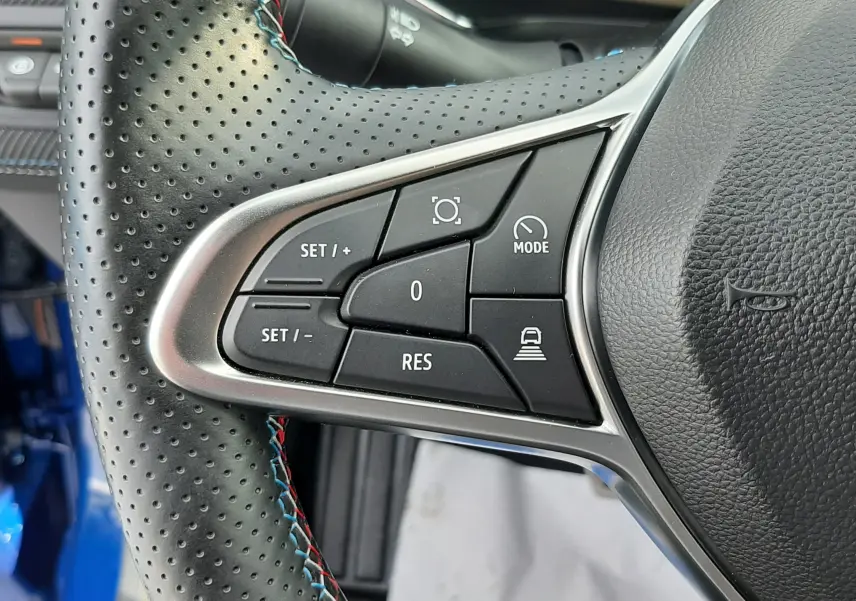Gros plan sur les commandes au volant en cuir perforé noir avec surpiqûres tricolores du Renault Captur bleu iron 2024.