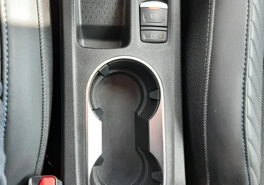 Gros plan sur la console centrale noire du Renault Captur 2024, avec porte-gobelets et commandes électroniques.