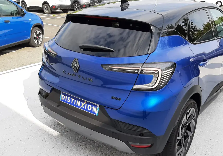 Vue 3/4 arrière d'un Renault Captur 2024 bleu iron avec toit noir, feux LED et jantes noires distinctives.