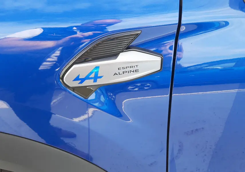 Gros plan sur l'emblème Esprit Alpine côté gauche d'un Renault Captur bleu iron avec toit noir.
