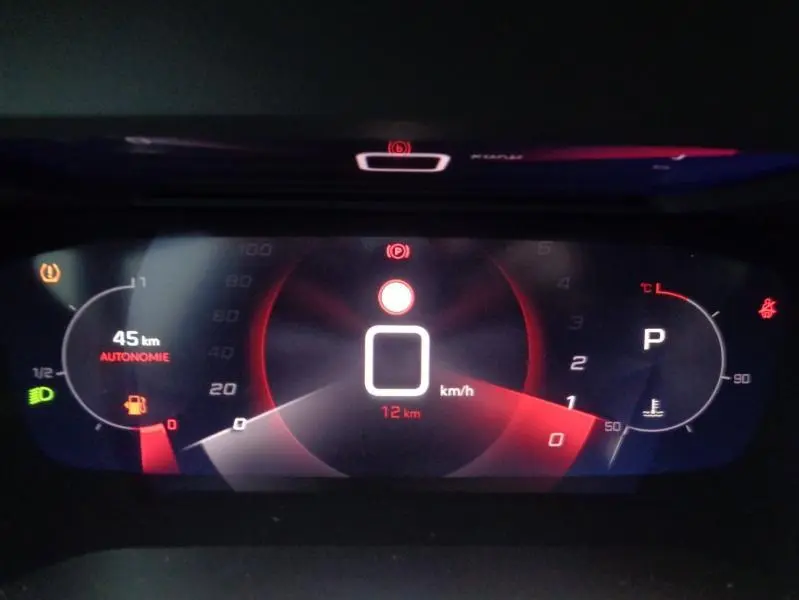 Tableau de bord numérique du Peugeot 2008 2023 affichant vitesse, autonomie et indicateurs d'alerte en rouge et blanc.