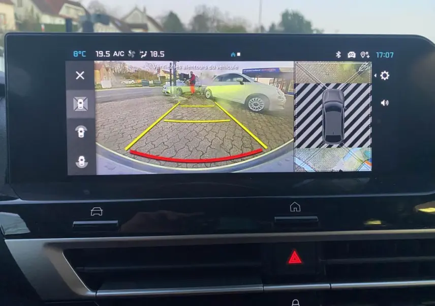 Écran de recul du Citroën C4 2025 gris foncé avec guidage jaune et rouge et vue 360° du stationnement.
