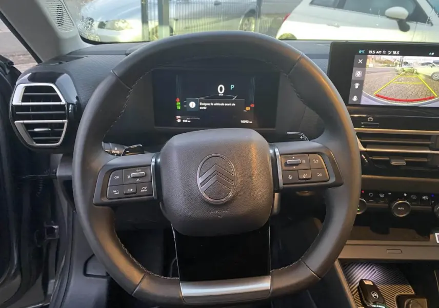 Vue frontale du volant et du tableau de bord numérique de la Citroën C4 2025, avec écran central affichant la caméra de recul.