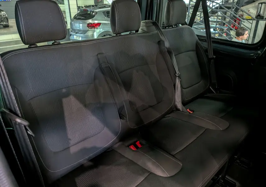 Vue intérieure de la banquette arrière en tissu noir du Nissan Primastar Combi 2025, avec ceintures de sécurité visibles.