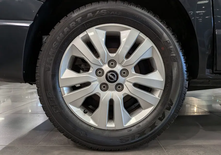 Gros plan sur la roue avant droite du Nissan Primastar Combi gris comète, avec jante alliage et pneu Maxxis Vansmart A/S.
