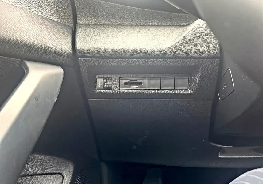 Détail de la console côté conducteur de la Peugeot 308 noire, montrant les commandes d'éclairage et les boutons vierges.