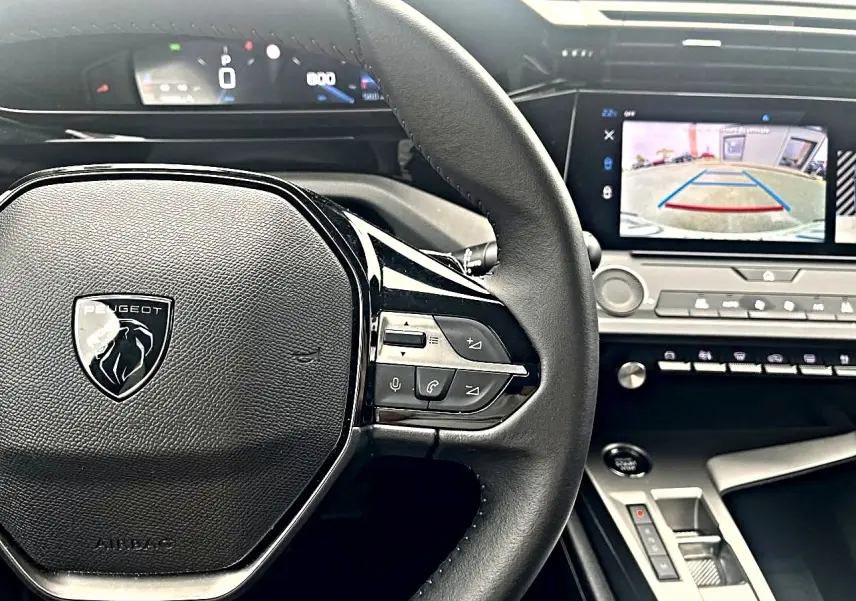 Vue rapprochée du volant noir Peugeot 308 2025 avec commandes multifonctions et écran tactile affichant la caméra de recul.