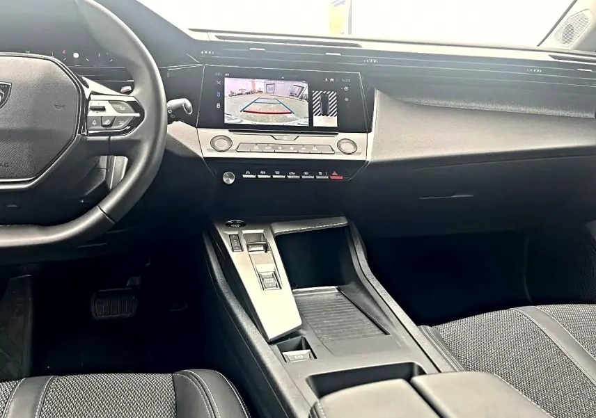 Vue intérieure avant de la Peugeot 308 noire, montrant le volant, écran tactile et console centrale moderne.