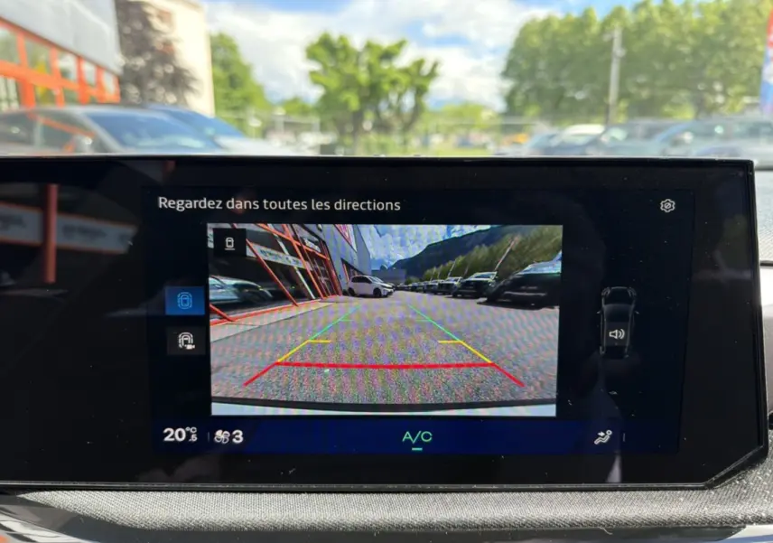 Affichage caméra de recul sur écran intérieur d'une Renault Clio blanc glacier, vue arrière avec lignes de guidage colorées.