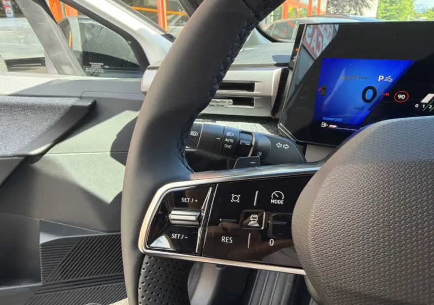 Gros plan sur le volant textile grainé et les commandes multifonctions d’une Renault Clio 6 TCE 115 EDC Techno.