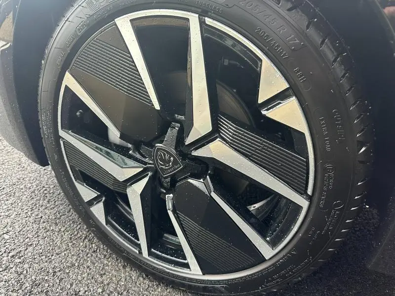Gros plan sur la jante noire et argentée du côté avant droit d'une Peugeot 208 1.2 Hybrid 110ch GT 2025.