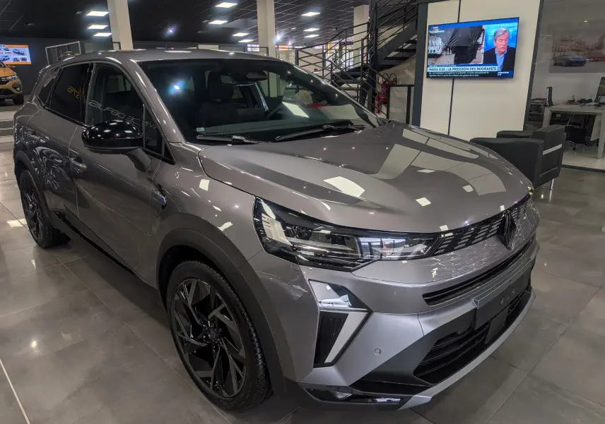 Renault Symbioz gris Cassiopé en 3/4 avant droit, mettant en valeur ses optiques LED et jantes noires brillantes.