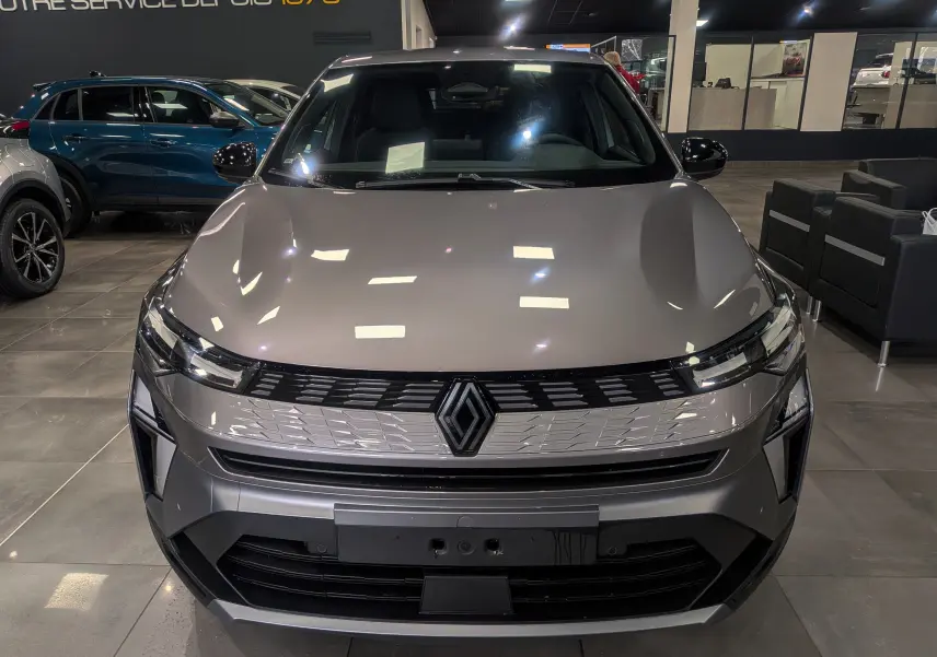 Vue avant d'un Renault SYMBIOZ gris Cassiopé en hybride, avec calandre moderne et logo Renault central lumineux.