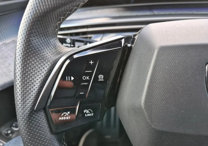 Gros plan sur les commandes du volant perforé du Peugeot 3008 Hybrid 136 e-DCS6 GT, finition noire brillante.