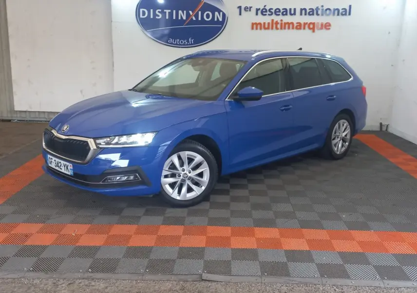Vue 3/4 avant droite d'une Skoda Octavia break bleu 2022, avec jantes alliage et phares LED allumés.