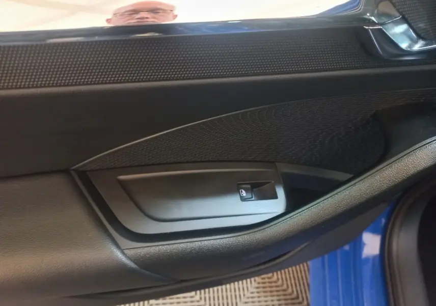 Intérieur côté conducteur de la porte d’une Skoda Octavia bleu 2022, avec commande de lève-vitre noir.