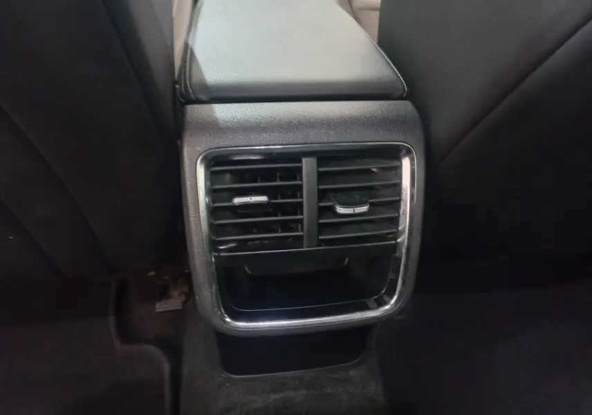 Gros plan sur la sortie d'air arrière centrale avec cadre chromé et console noire dans une Skoda Octavia bleue 2022.