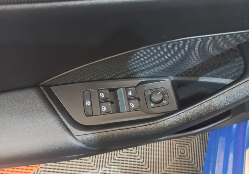 Gros plan sur les commandes électriques des vitres et rétroviseurs côté conducteur d’une Skoda Octavia bleu 2022.