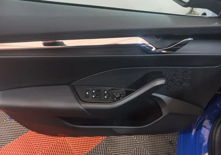 Vue intérieure côté gauche de la porte avant d’une Skoda Octavia bleue avec commandes électriques et garniture noire.
