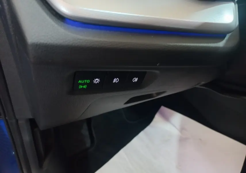 Détail des commandes d'éclairage avec rétroéclairage bleu à gauche côté conducteur d'une Skoda Octavia bleue 2022.