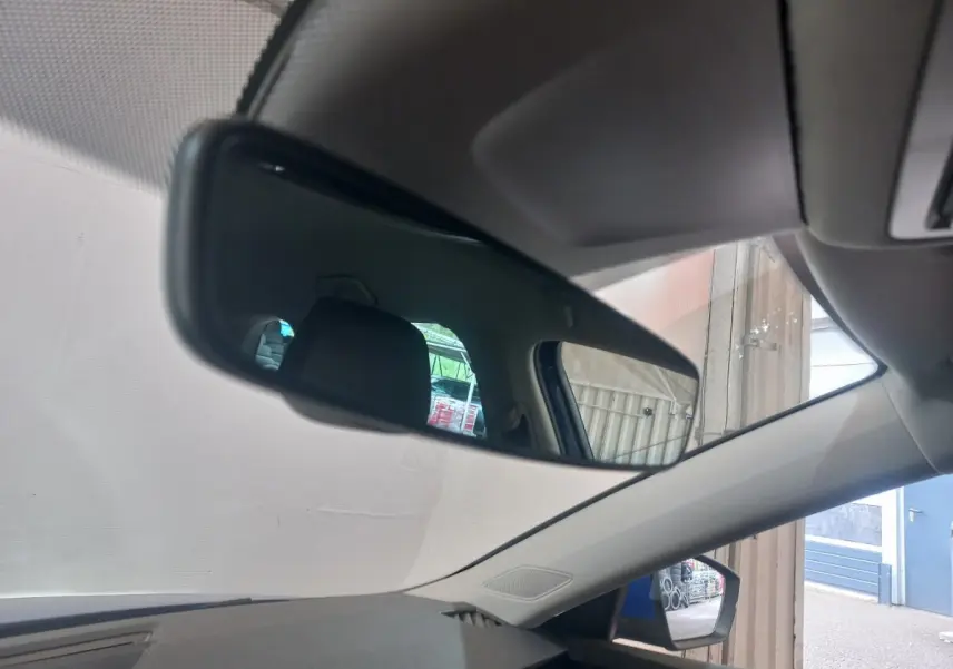 Vue intérieure du rétroviseur central d'une Skoda Octavia 1.5 TSI bleu, avec reflet du siège arrière et fenêtre latérale.