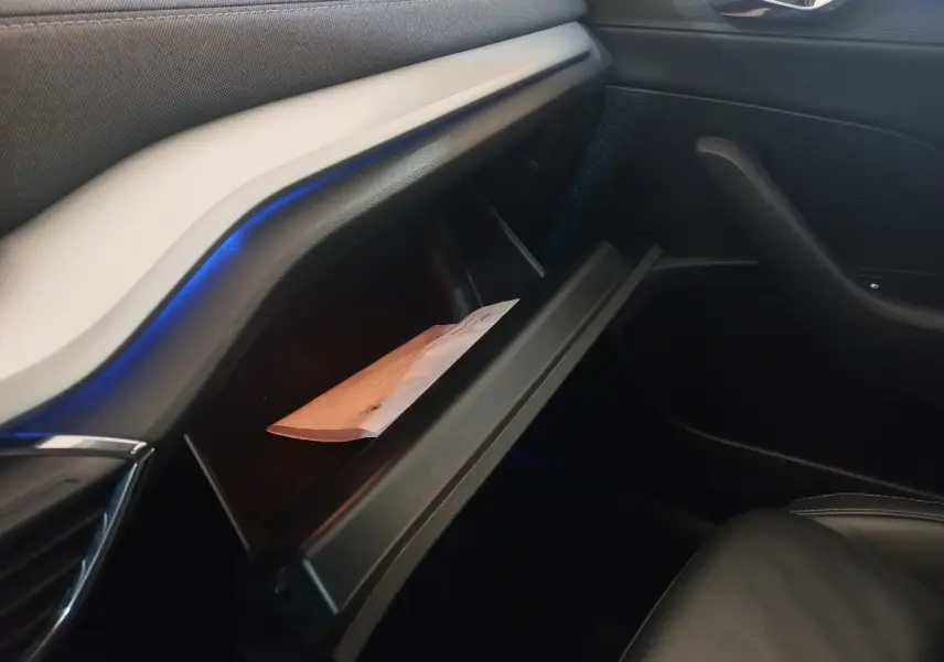 Intérieur de la Skoda Octavia 2022, vue côté passager sur la boîte à gants ouverte avec éclairage d’ambiance bleu.