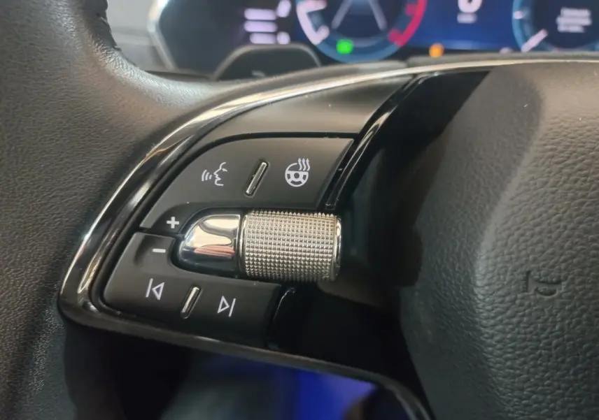 Gros plan sur les commandes gauche du volant cuir noir de la Skoda Octavia 2022 avec molette métallique et boutons tactiles.