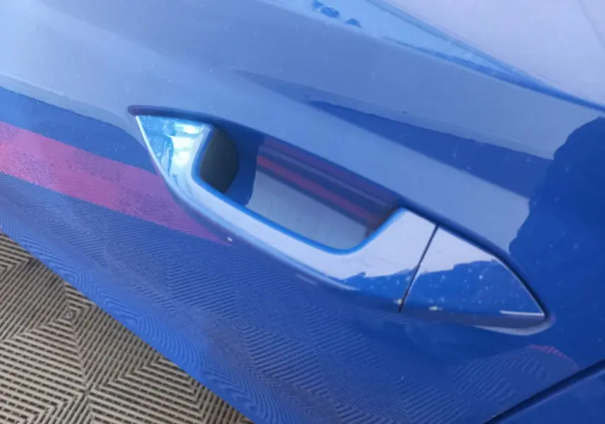 Poignée de porte côté gauche bleu brillant d'une Skoda Octavia 1.5 TSI mHEV e-TEC 2022, vue rapprochée.