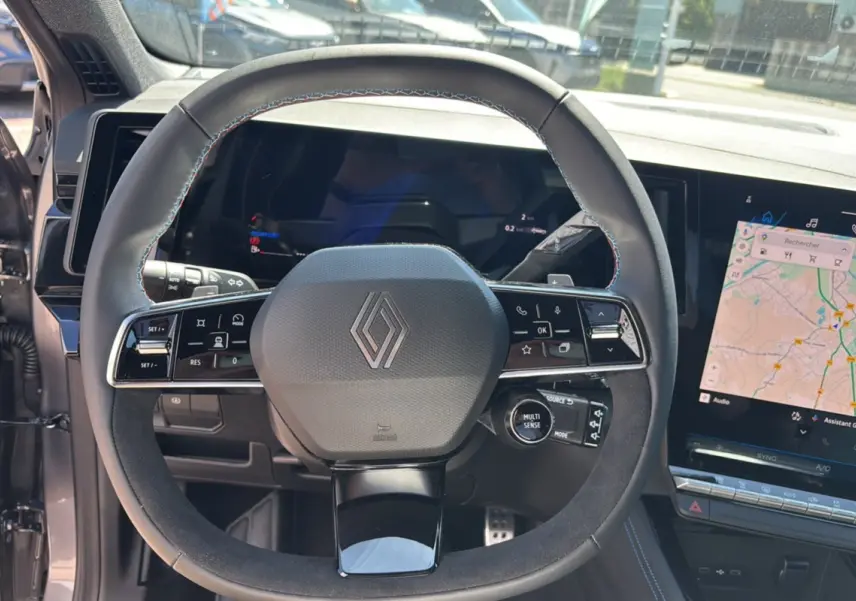 Vue rapprochée du volant cuir multifonctions avec logo Renault et écran tactile GPS sur Renault Austral E-Tech 200 Esprit Alpine.