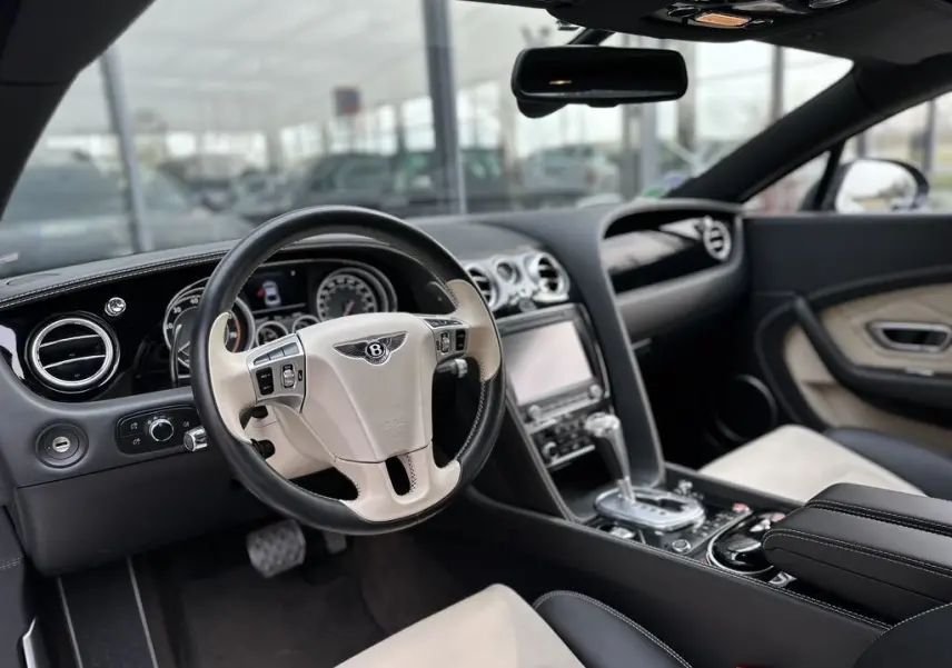 Intérieur de la Bentley Continental GT Mulliner 2013, vue côté conducteur, volant cuir bicolore noir et beige avec tableau de bord élégant.