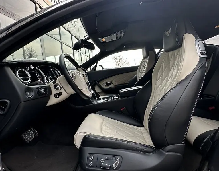 Intérieur de la Bentley Continental GT 4.0 V8 Mulliner 2013 vue côté conducteur, sièges cuir noir et beige avec logo brodé.