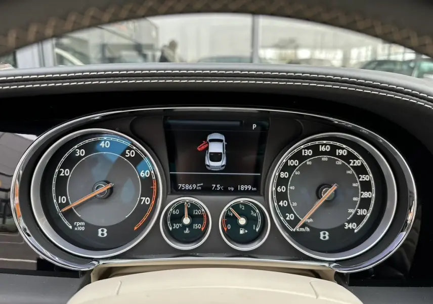 Tableau de bord de Bentley Continental GT Mulliner 2013, avec compteurs analogiques et écran central affichant une porte ouverte.