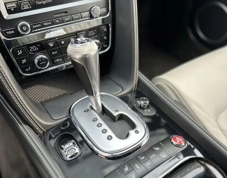 Gros plan sur la console centrale noire de la Bentley Continental GT 4.0 V8 Mulliner 2013 avec levier de boîte auto et écran navigation.