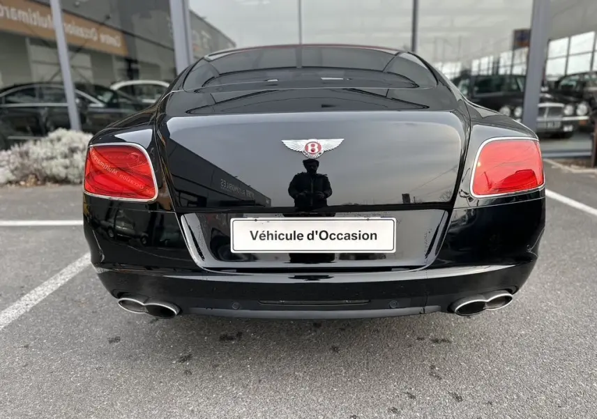 Vue arrière d'une Bentley Continental GT 4.0 V8 Mulliner noire de 2013 avec feux rouges et double sortie d'échappement chromée.