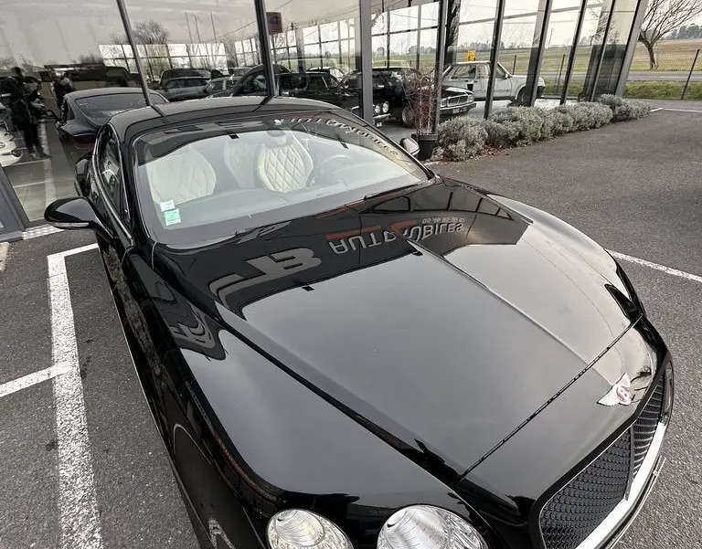 Bentley Continental GT Mulliner noire vue en 3/4 avant droit, mettant en valeur ses phares ronds et la calandre distinctive.