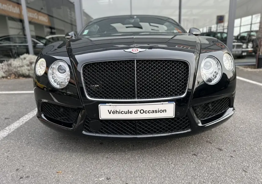 Vue frontale rapprochée de la Bentley Continental GT Mulliner noire de 2013 avec sa calandre distinctive et ses phares ronds.