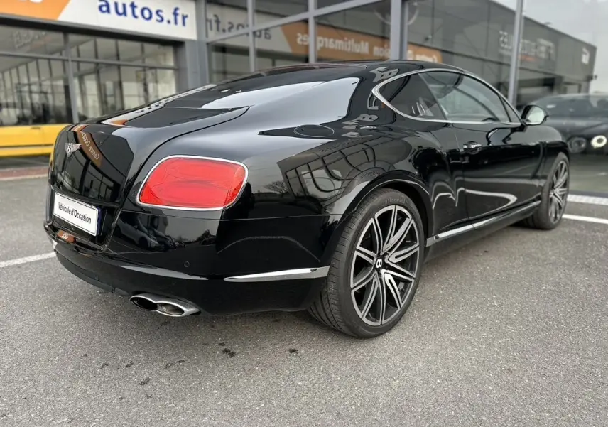 Bentley Continental GT 4.0 V8 Mulliner noire vue 3/4 arrière droit, avec jantes alliage distinctives et feux rouges.