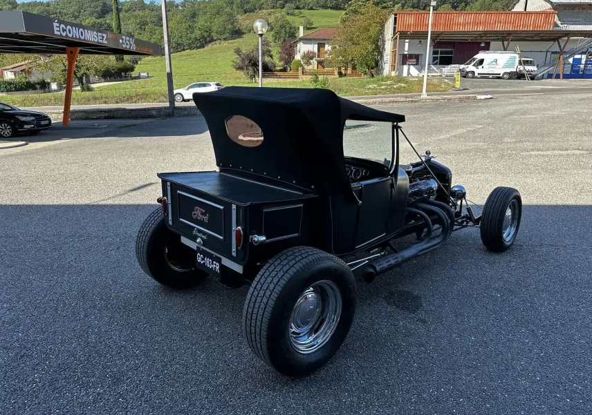 Vue 3/4 arrière droite d'une Ford T Hot Rod V8 noire décapotable avec moteur apparent et jantes chromées.