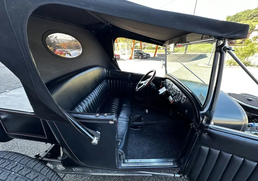 Vue latérale gauche de l'intérieur noir cuir du Ford T Hot Rod V8 1923 avec capote et tableau de bord visible.
