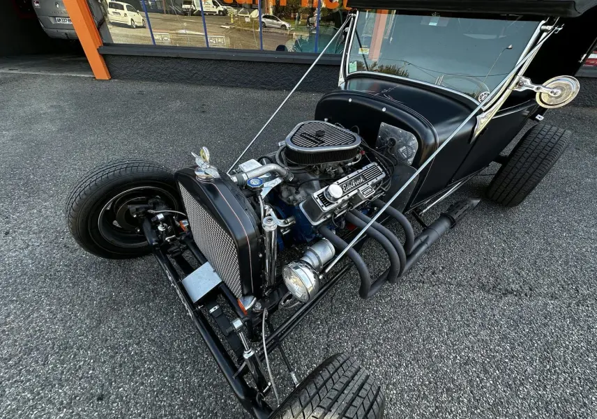 Vue 3/4 avant droite d'une Ford T Hot Rod noire avec moteur V8 visible et échappements latéraux exposés.