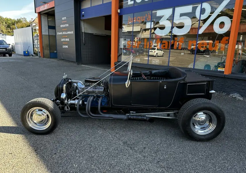 Ford T Hot Rod V8 noir vu de profil côté gauche, moteur apparent et intérieur cuir noir décapotable.