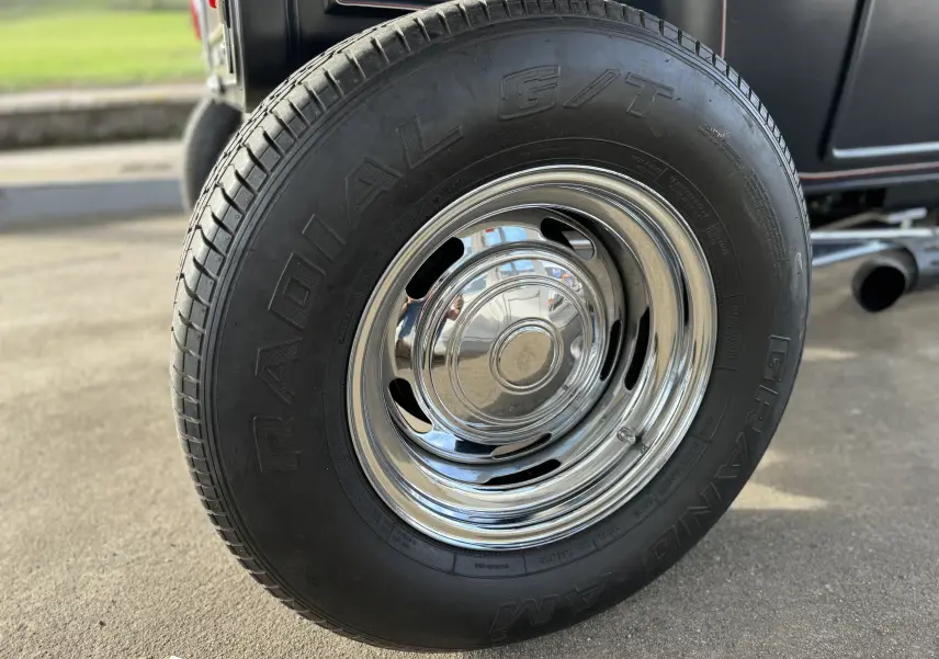 Gros plan sur la roue arrière droite chromée du Ford T Hot Rod noir de 1923 avec pneus Radial G/T.